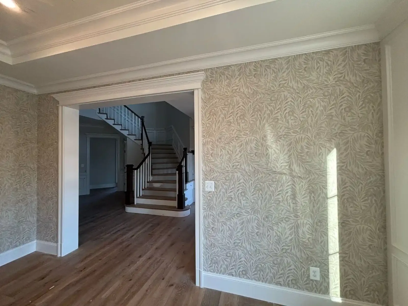 Elegant dark floral wallpaper installed around a fireplace in a Converse home