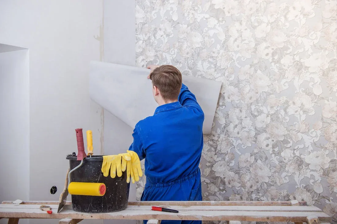 Valora installer measuring and cutting wallpaper on a preparation table