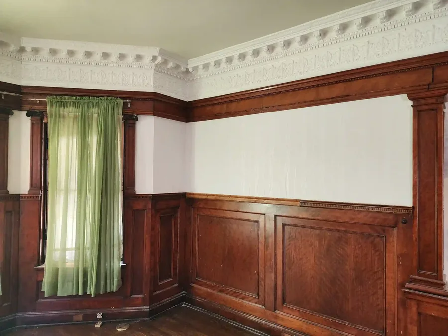 Period-appropriate wallpaper installed in a historic home parlor with green drapes