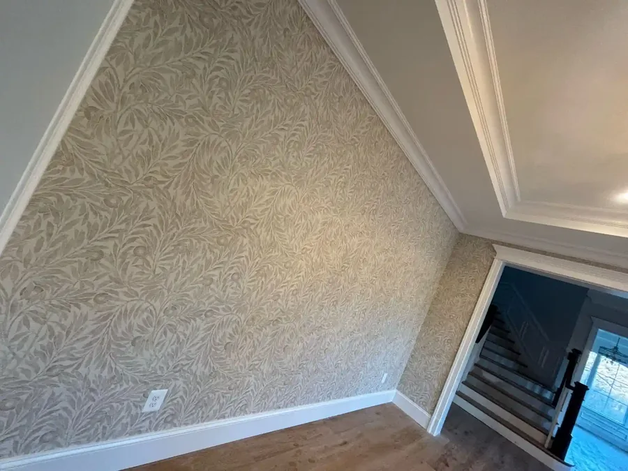 Grey floral wallpaper surrounding an arched window in a stairwell
