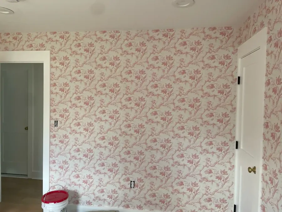 Rich red tapestry-style wallpaper installed above wainscoting in a formal dining room