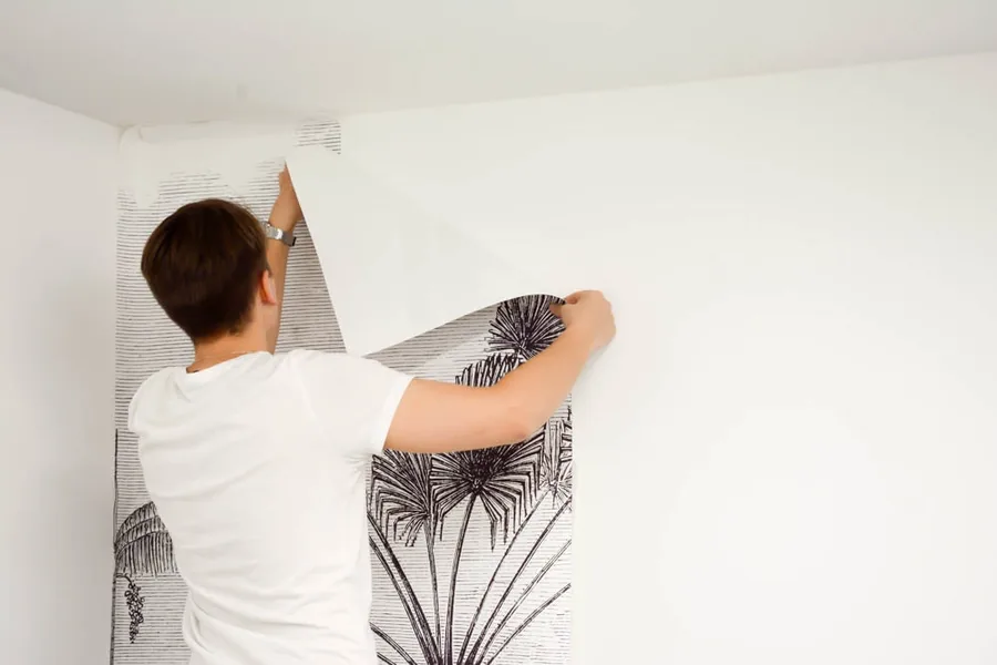 Technician peeling old wallpaper from a wall during professional removal